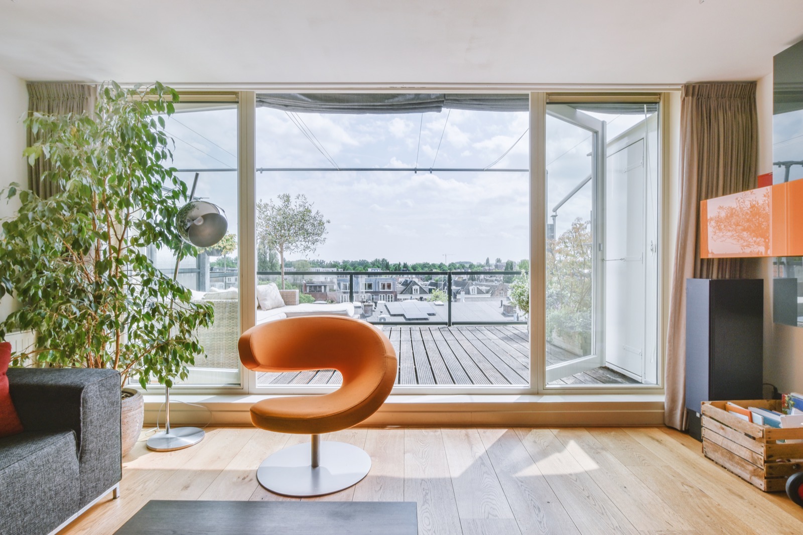 Salón luminoso de un piso con una gran cristalera que da a una terraza y a los tejados de la ciudad